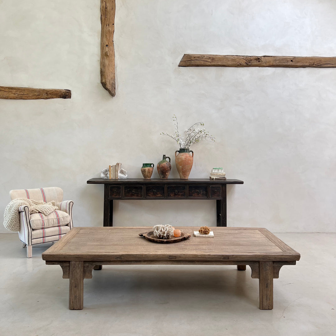 Rustic wooden coffee table and console table against a white wall with decorative items.