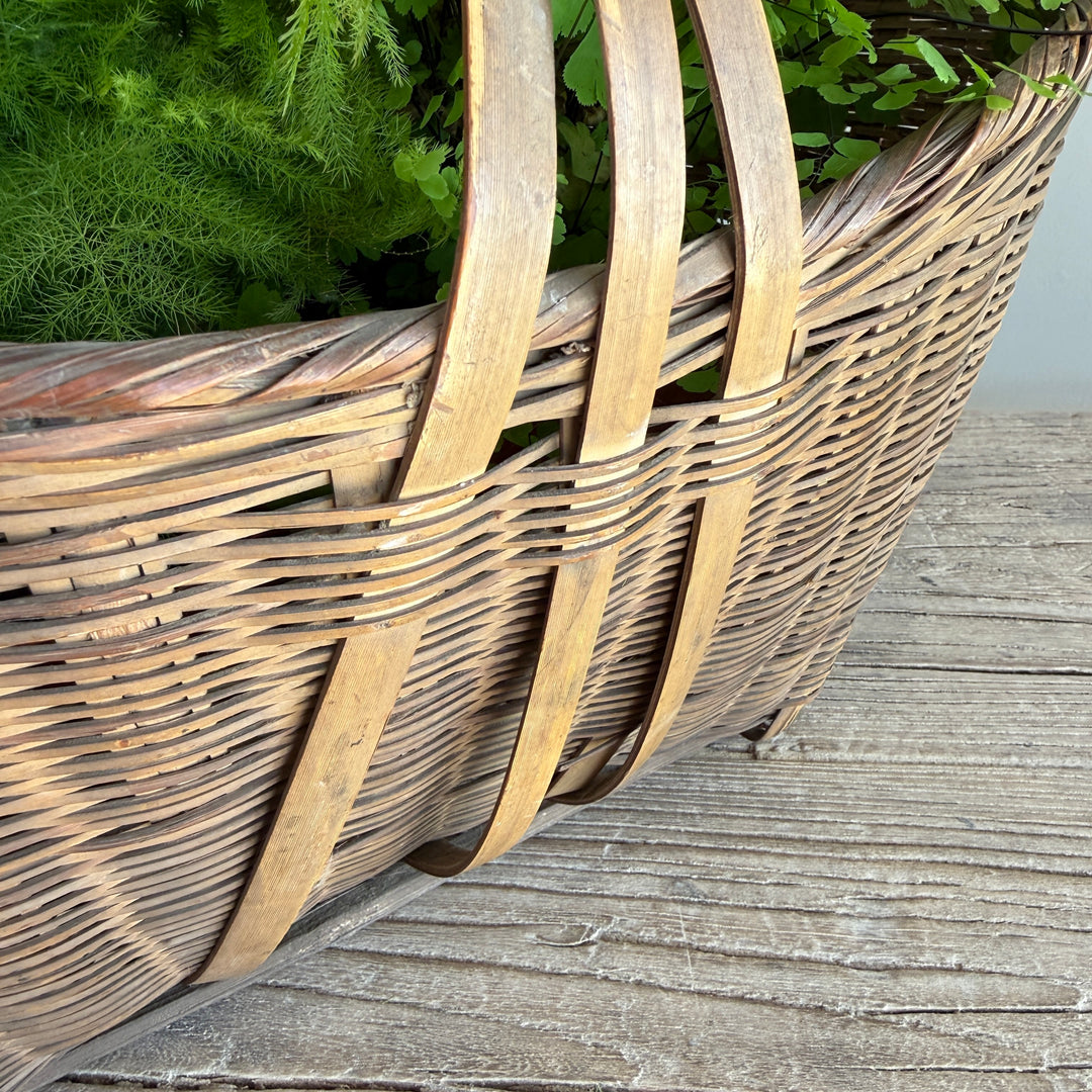 Wicker basket on a wooden deck with greenery in the background