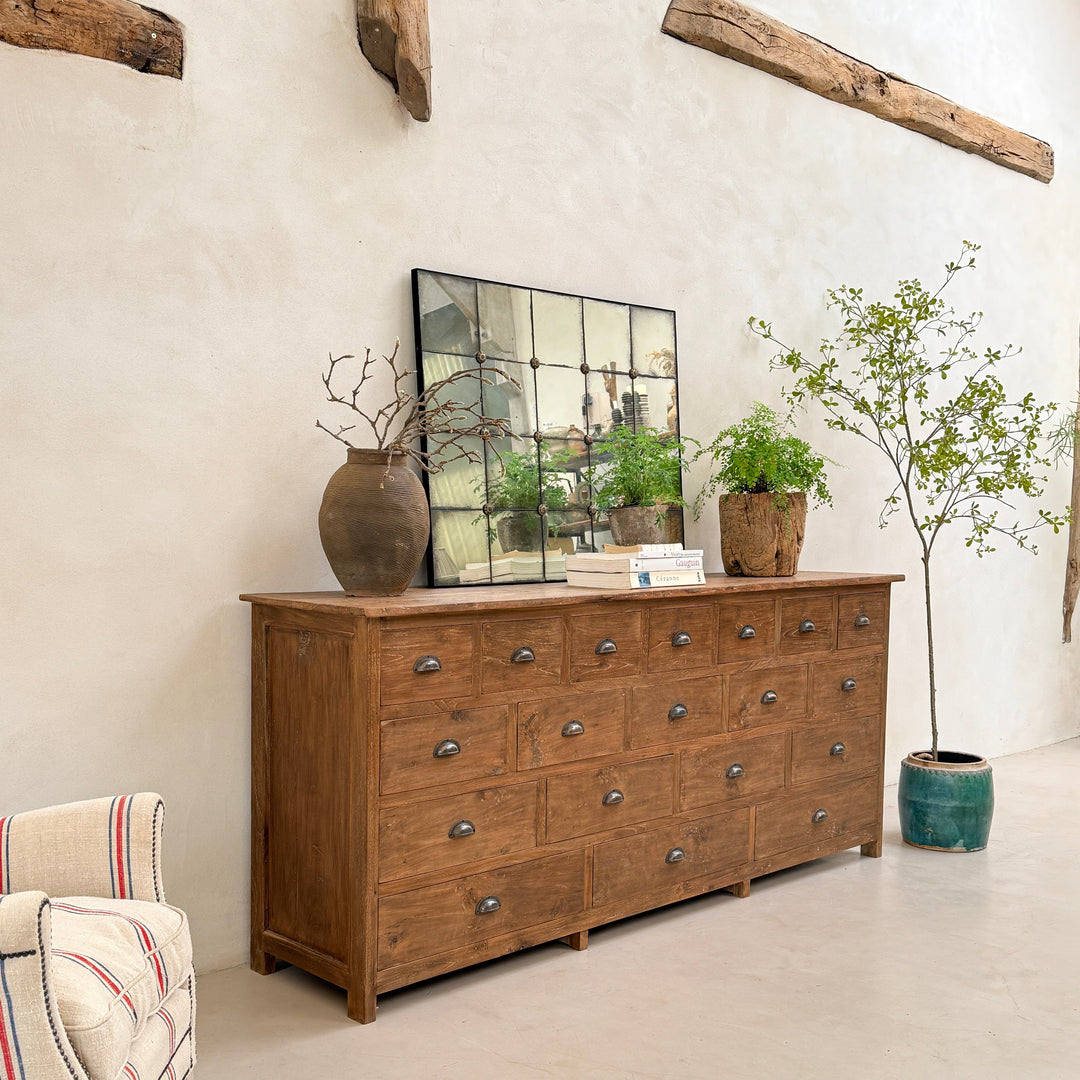 The Chiswick Dark Wood Multi Drawer Chest handcrafted from solid teak, styled beneath a statement mirror in a contemporary country interior. Inspired by traditional apothecary cabinets, this beautifully crafted storage piece features multiple functional drawers, rich natural timber grain and timeless proportions, making it an elegant choice for entrance halls, dining rooms and living spaces.
