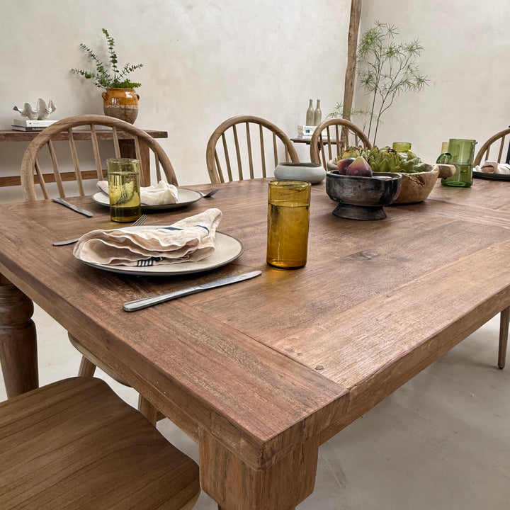 A contemporary country dining table beautifully styled for entertaining, combining reclaimed teak, artisan tableware and understated interior design for relaxed modern living.