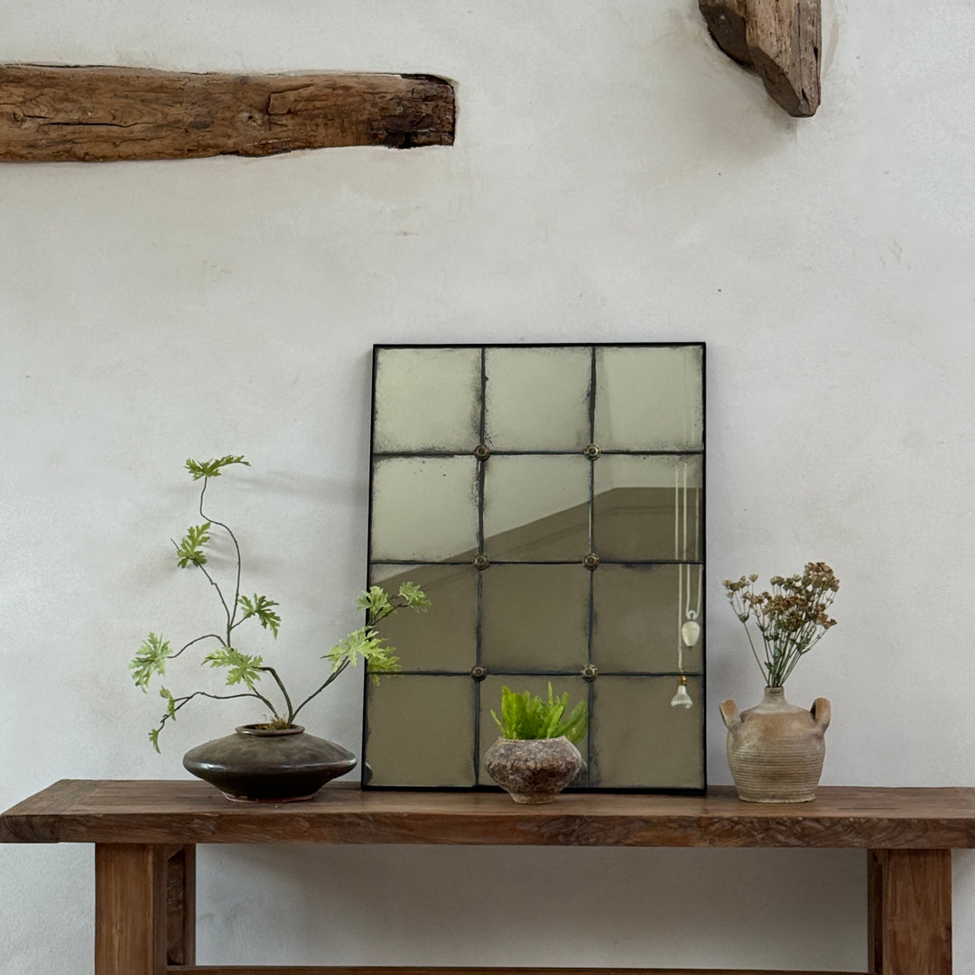 Cosima foxed antiqued mirror with hand-distressed Verre Églomisé glass and decorative brass rosettes, styled on a reclaimed teak console table in a contemporary country entrance hall.