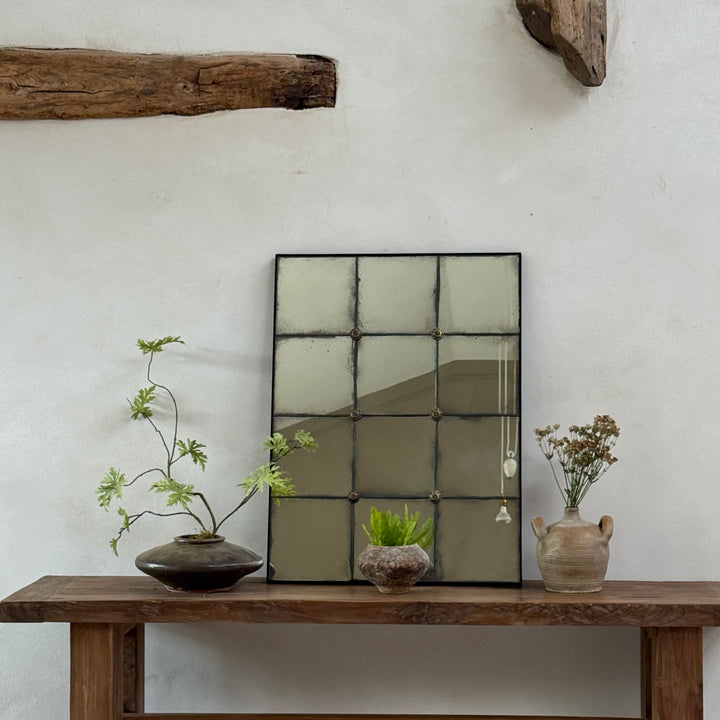 Cosima foxed antiqued mirror with hand-distressed Verre Églomisé glass and decorative brass rosettes, styled on a reclaimed teak console table in a contemporary country entrance hall.