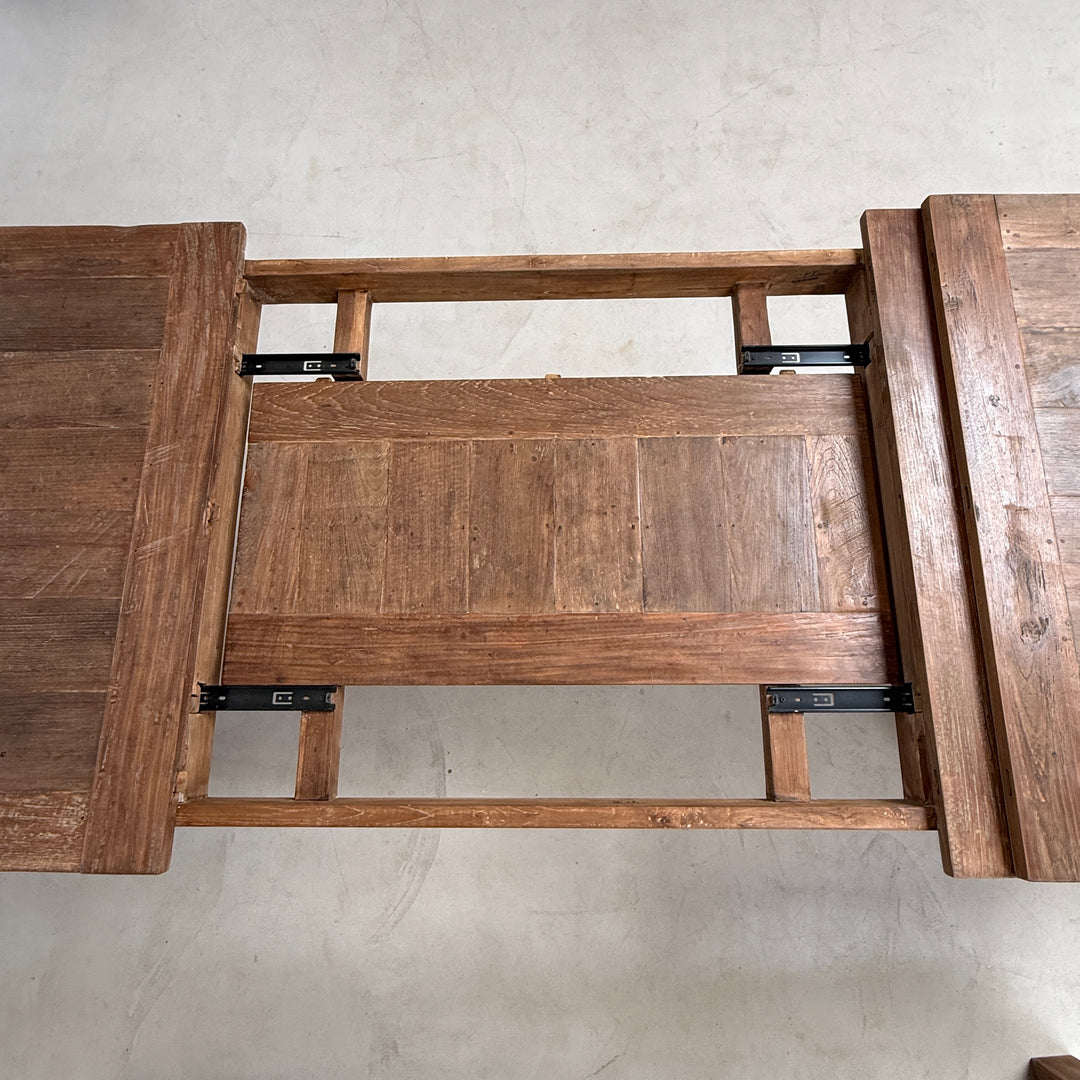 The extending teak dining table shown during extension, demonstrating the smooth extension system and additional seating capacity for entertaining guests with ease.