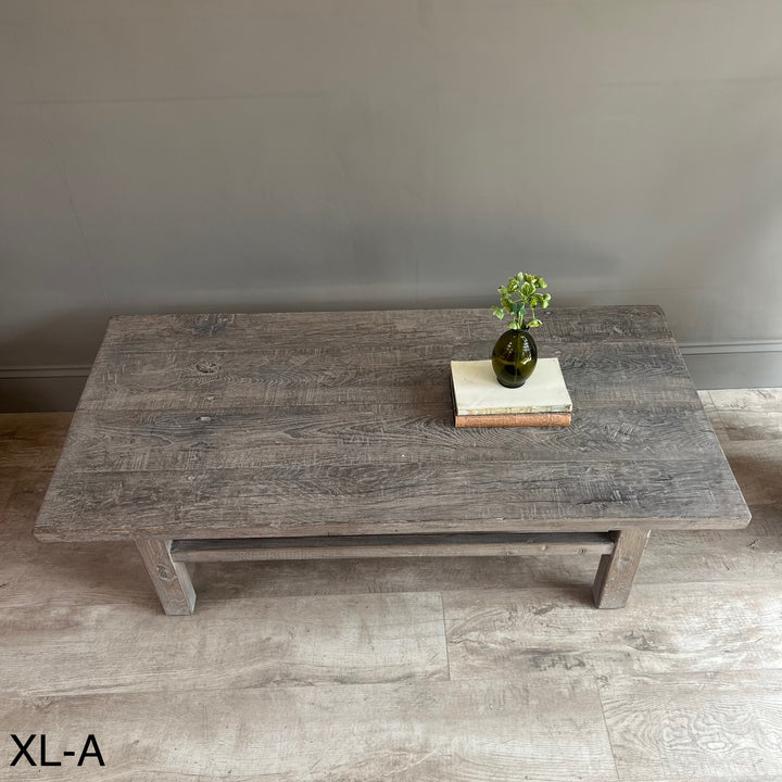 Wooden coffee table with decorative items on a gray floor and wall background