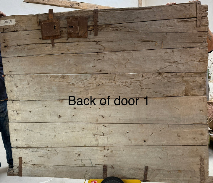 Wooden door with 'Back of door 1' text, showing signs of wear and rust.