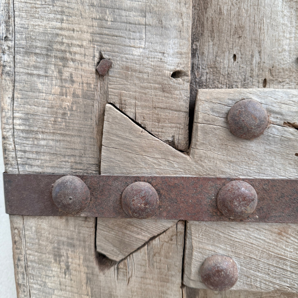 Close-up of a wooden door with metal strap and nails