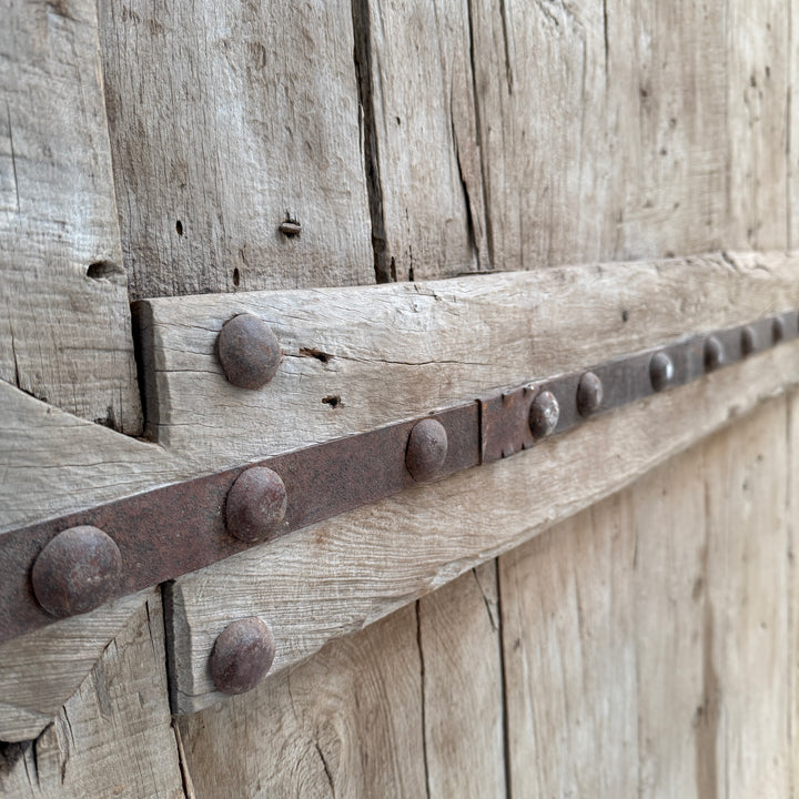 Close-up of a wooden door with metal strap and nails