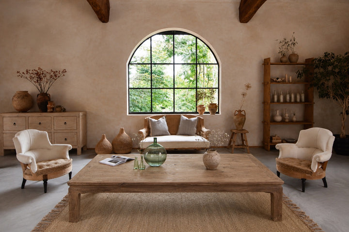 Living room with wooden coffee table, armchairs, and a large window.
