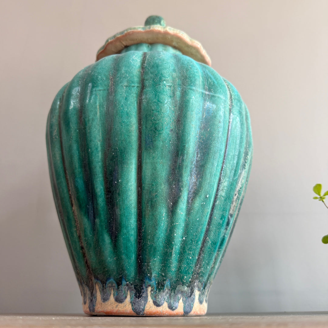 Rear view of a green glazed stoneware temple jar, showcasing its fluted silhouette and richly layered green crackle glaze.
