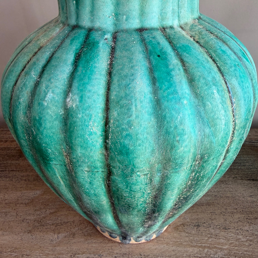 Close-up of the ribbed body of a handcrafted green glazed stoneware temple jar, showcasing its sculptural form and richly textured crackle glaze.
