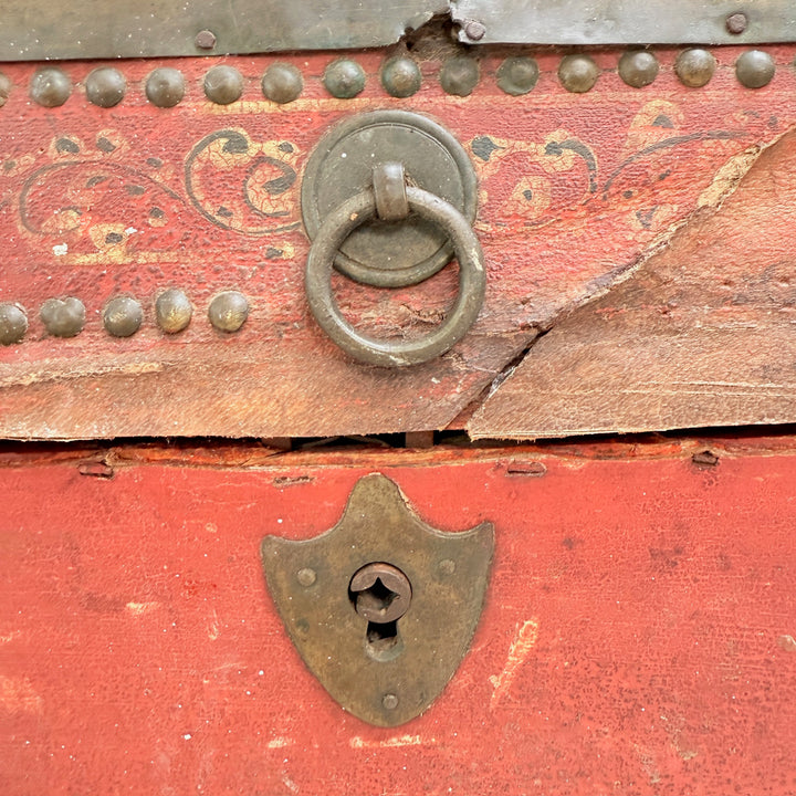 Close-up of a red wooden chest with metal ring handle and lock.
