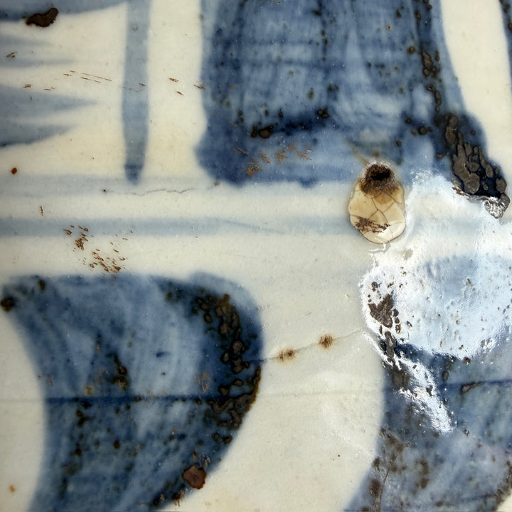 Close-up of the artisan hand-painted brushwork and aged detailing on a blue and white porcelain vase inspired by traditional Chinese ceramics.
