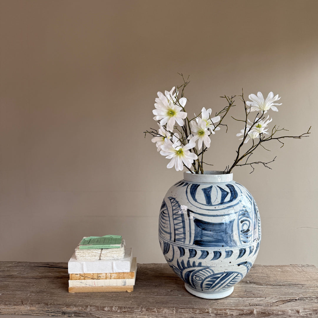 Hand-painted blue and white porcelain vase styled with delicate blossom stems on a reclaimed wooden console, inspired by traditional Chinese ceramics for a contemporary country home.
