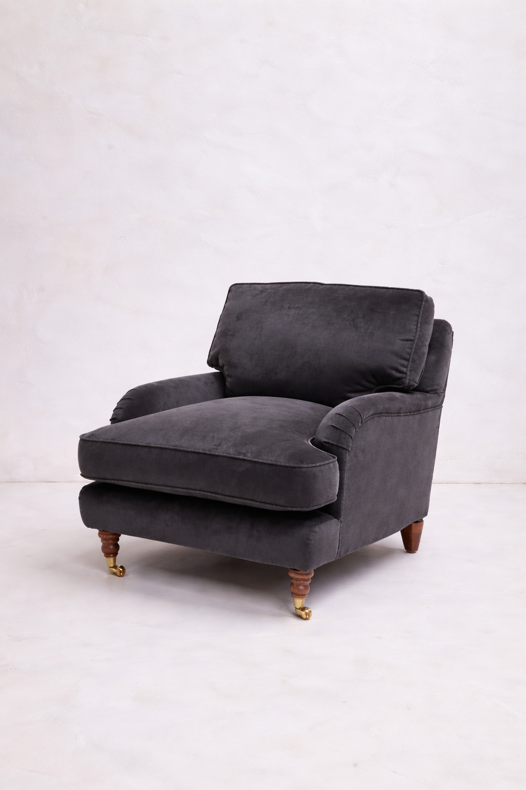 Dark grey velvet aremchair in white studio
