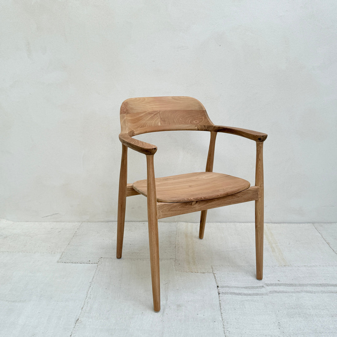 Wooden chair with armrests on a white floor and light gray wall