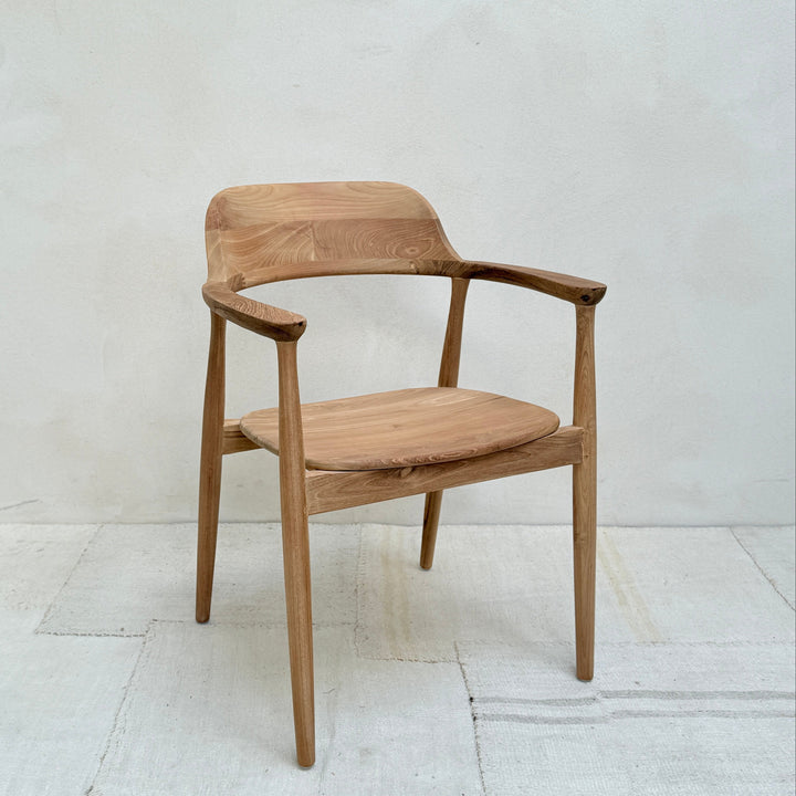 Wooden chair with armrests on a white floor and light gray wall
