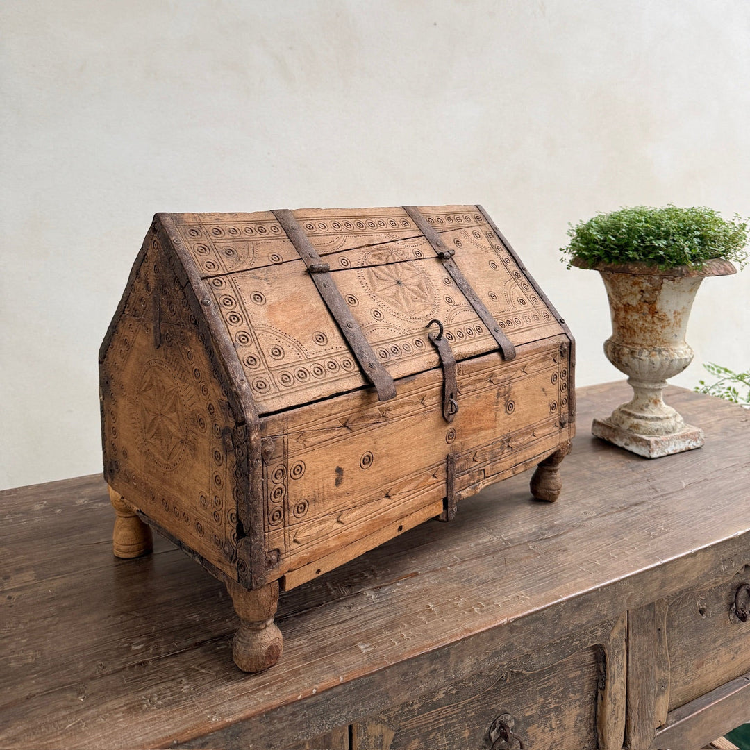 Vintage wooden chest on a rustic wooden surface with a white wall background