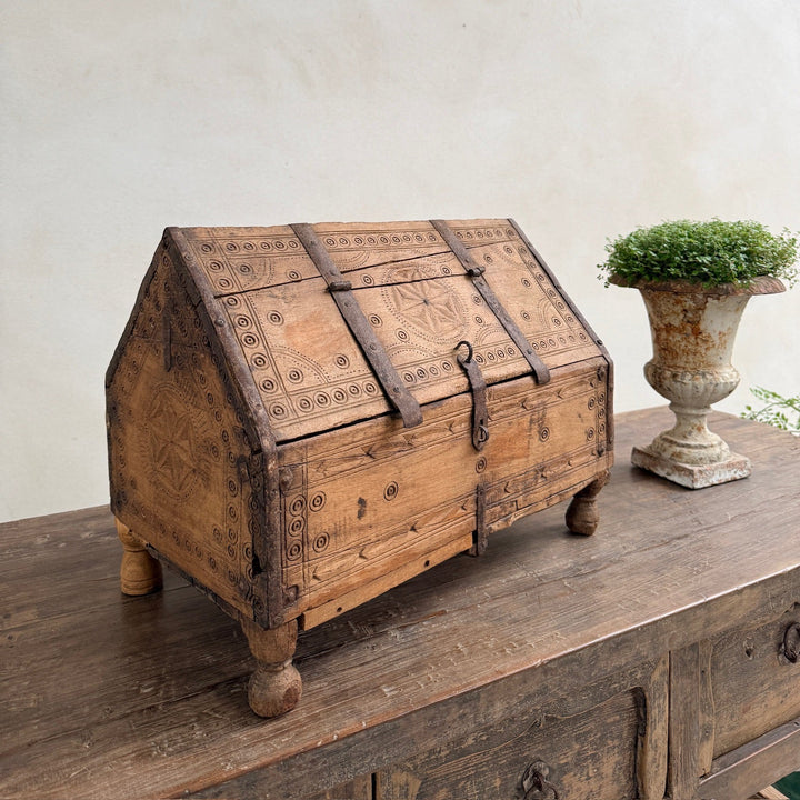 Vintage wooden chest on a rustic wooden surface with a white wall background