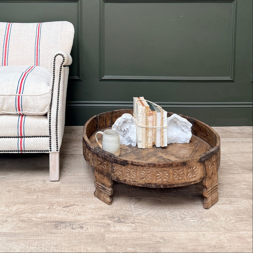 Chair with striped cushion next to a wooden coffee table against a green paneled wall.