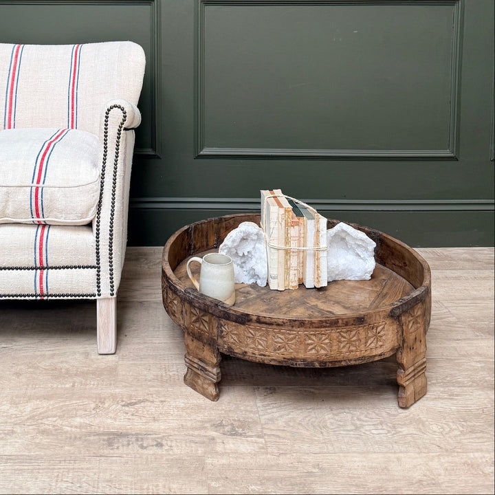 Chair with striped cushion next to a wooden coffee table against a green paneled wall.