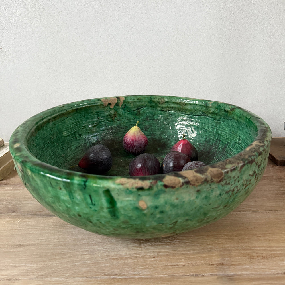 Green ceramic bowl with figs on a wooden surface