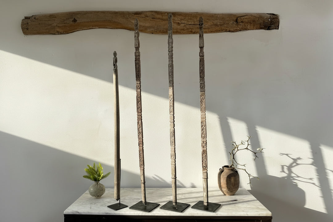 set of four carved wooden antique totem poles which are antique on a marble table