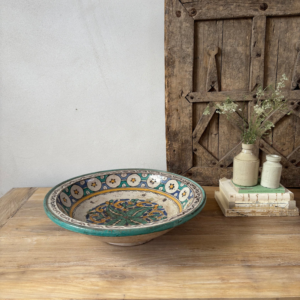 Decorative ceramic bowl on a wooden surface with a rustic wooden door in the background.