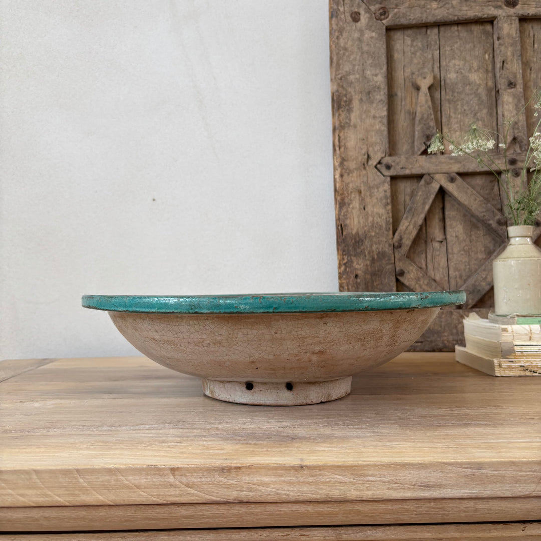 Ceramic bowl with green interior on a wooden surface with a rustic background