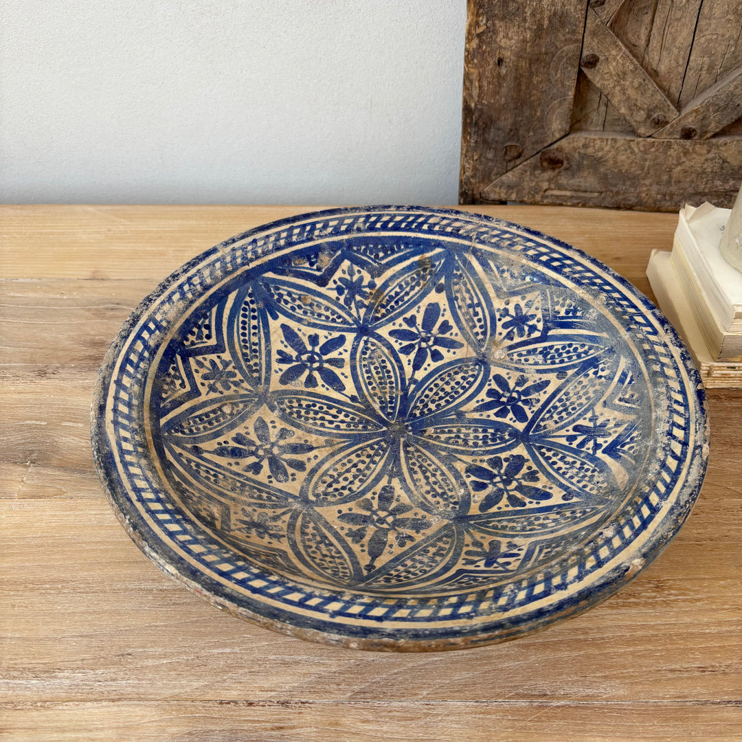 Decorative ceramic plate with blue and beige pattern on a wooden surface