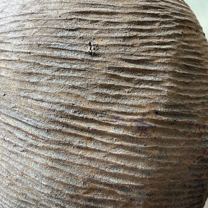 Detail of the hand-combed stoneware surface on a large antique Chinese storage jar, showcasing its unique texture and historic craftsmanship.
