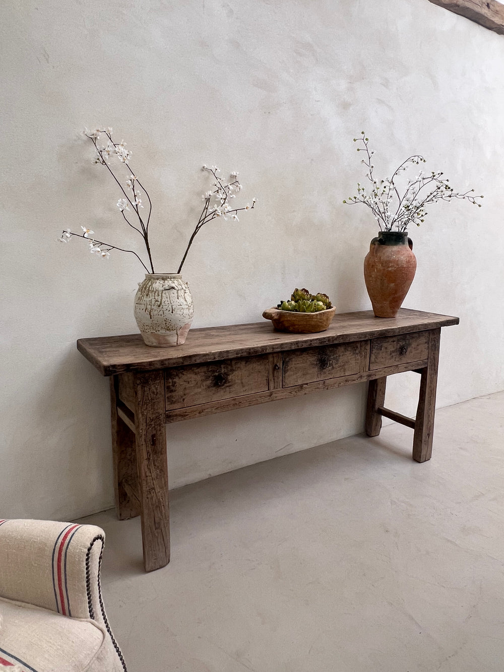 Wooden stool with decorative vases on a light gray floor
