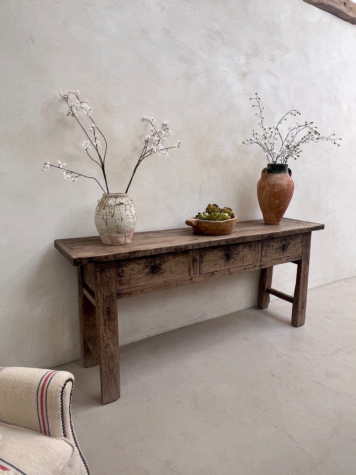 Wooden stool with decorative vases on a light gray floor