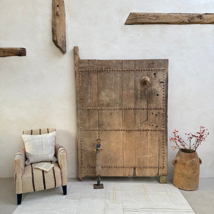 Vintage wooden door in a room with a chair and decorative elements.