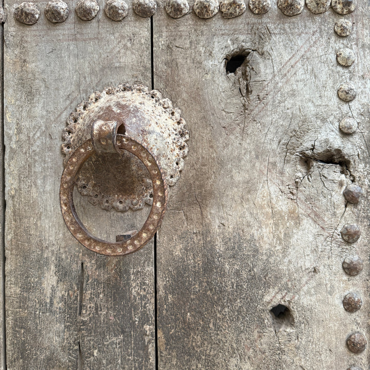 Rustic metal door handle on a textured wooden door