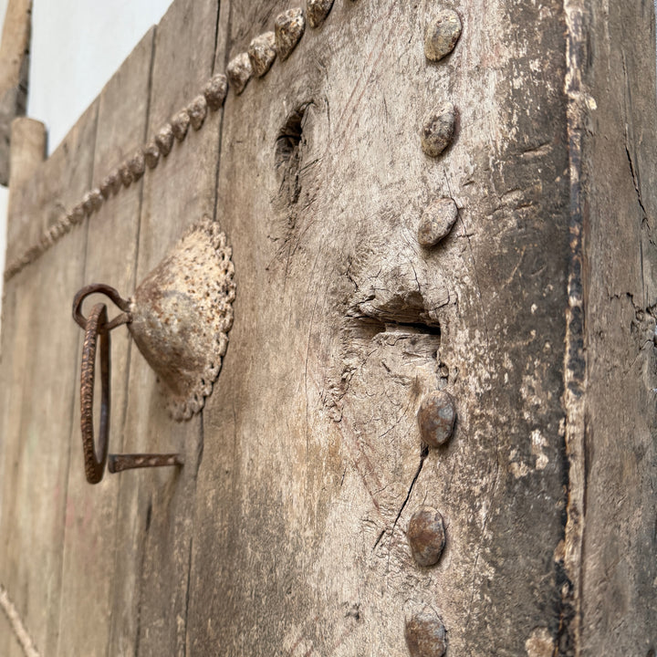 Close-up of an old wooden door with metal fixtures and a rusty handle.