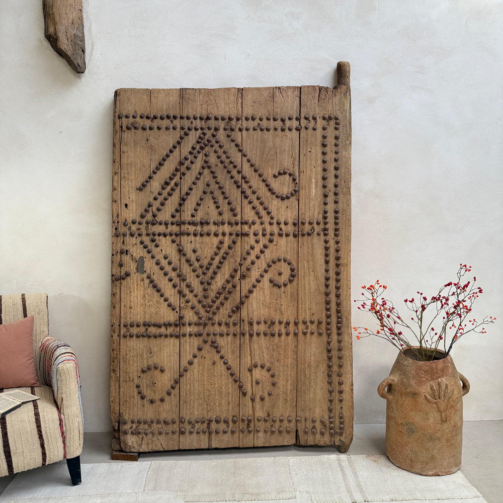 Decorative wooden panel with geometric patterns in a room with a chair and vase.