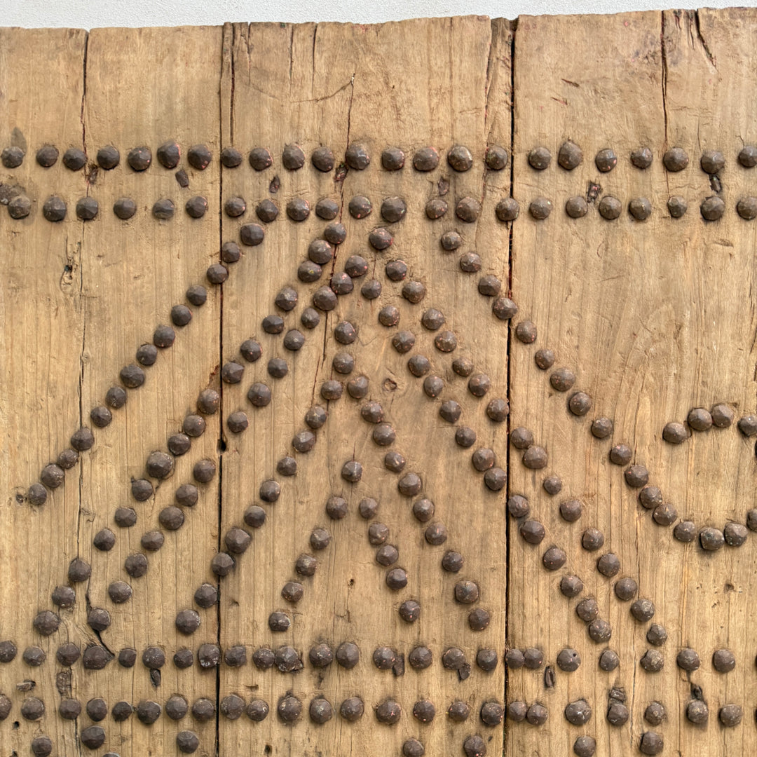 Wooden panel with metal rivets arranged in a decorative pattern