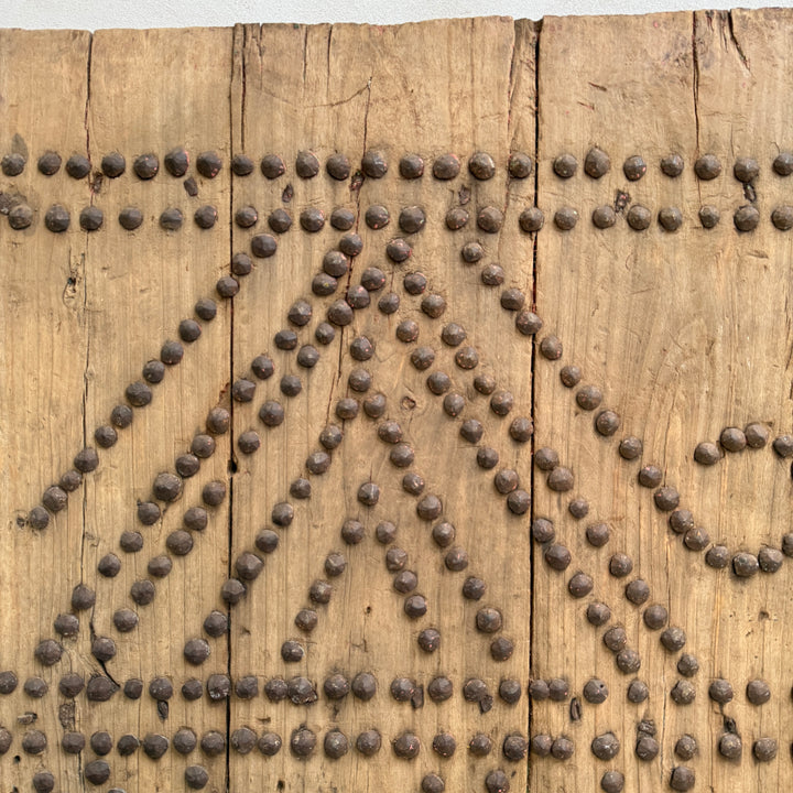 Wooden panel with metal rivets arranged in a decorative pattern