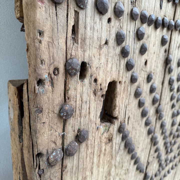 Close-up of a wooden surface with metal nails and a gray background