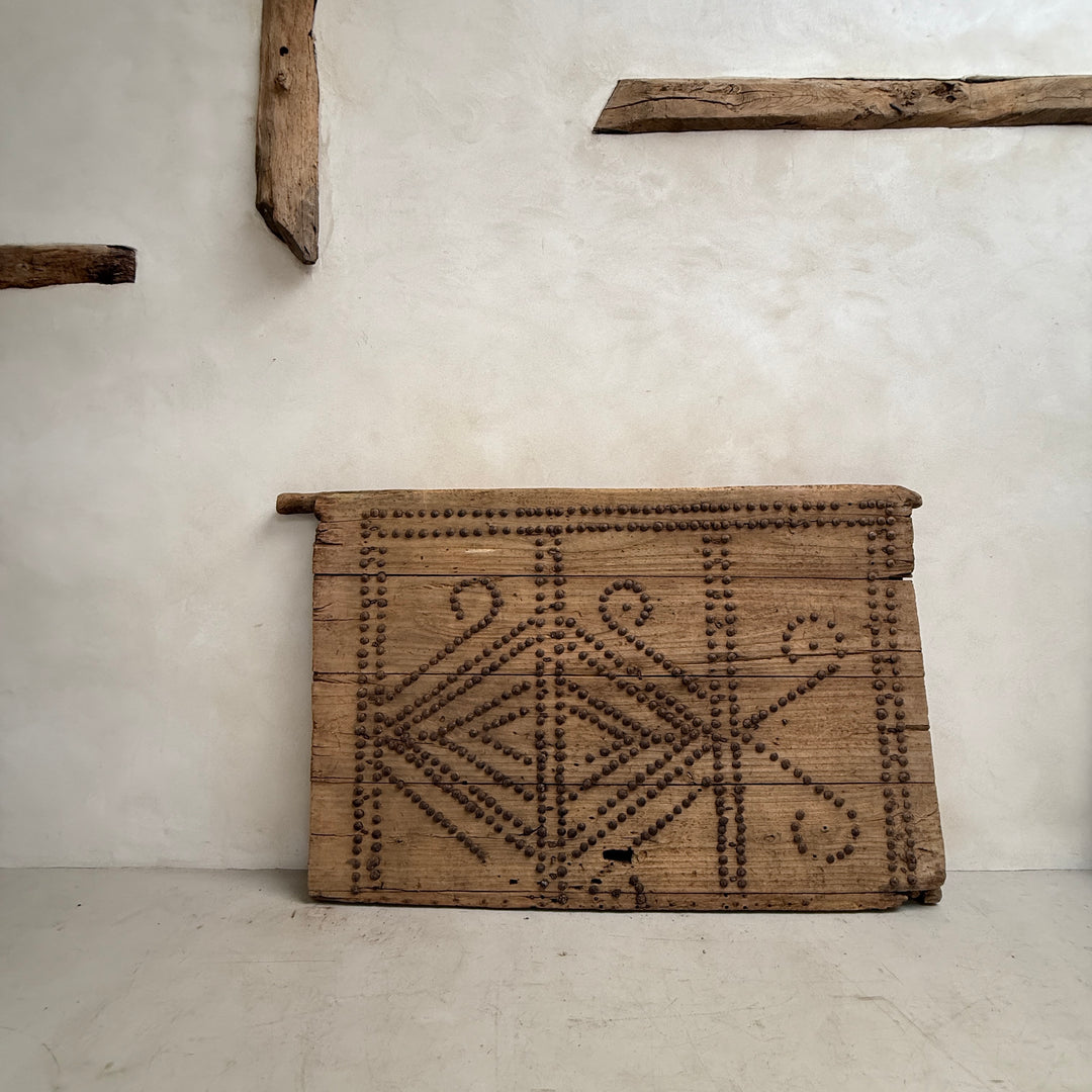 Wooden box with geometric patterns against a plain wall