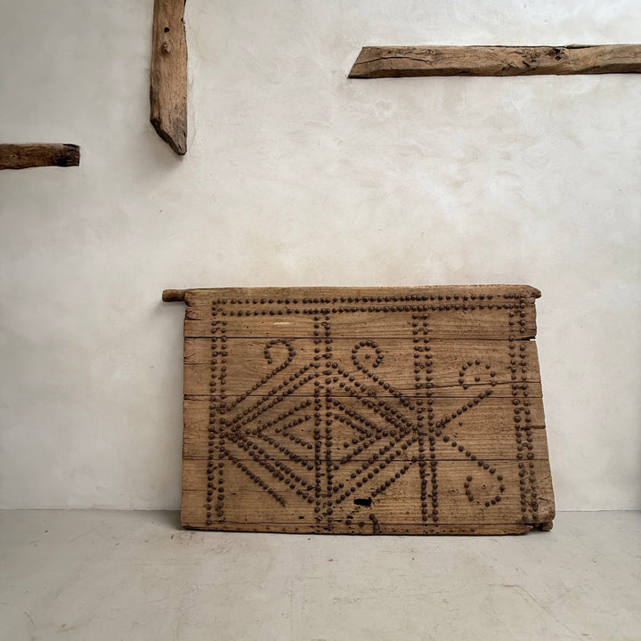 Wooden box with geometric patterns against a plain wall