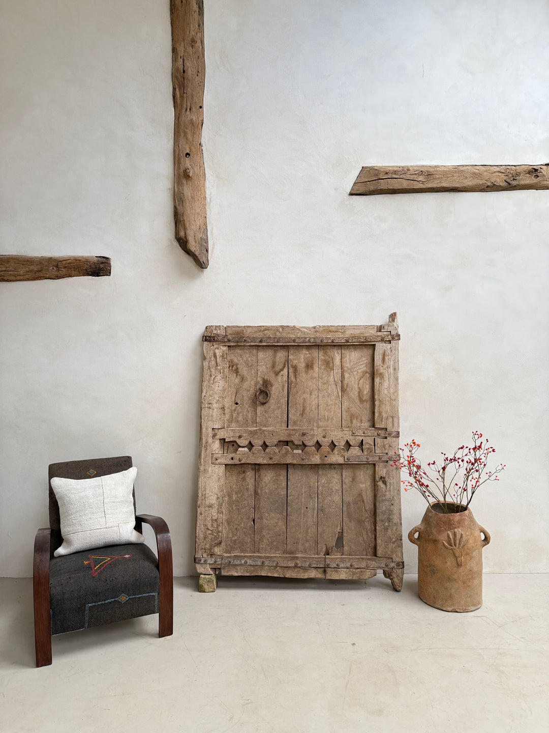 Vintage wooden panel on a wall with a rustic chair and decorative vase.
