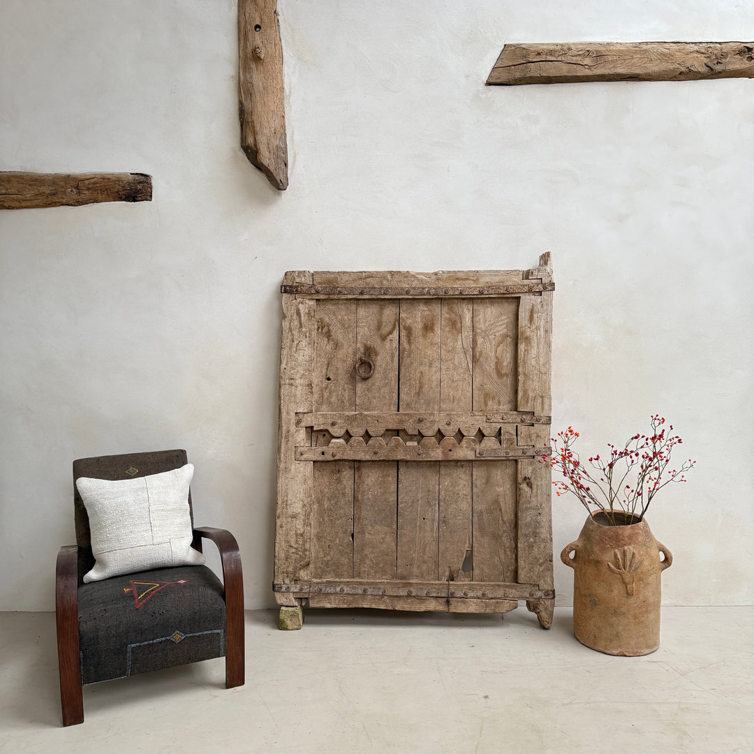 Vintage wooden cabinet with a chair and vase against a white wall