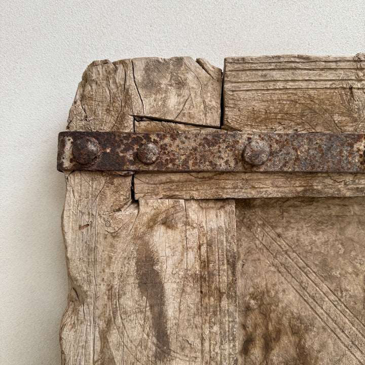 Close-up of a rustic wooden door with metal hardware on a white background