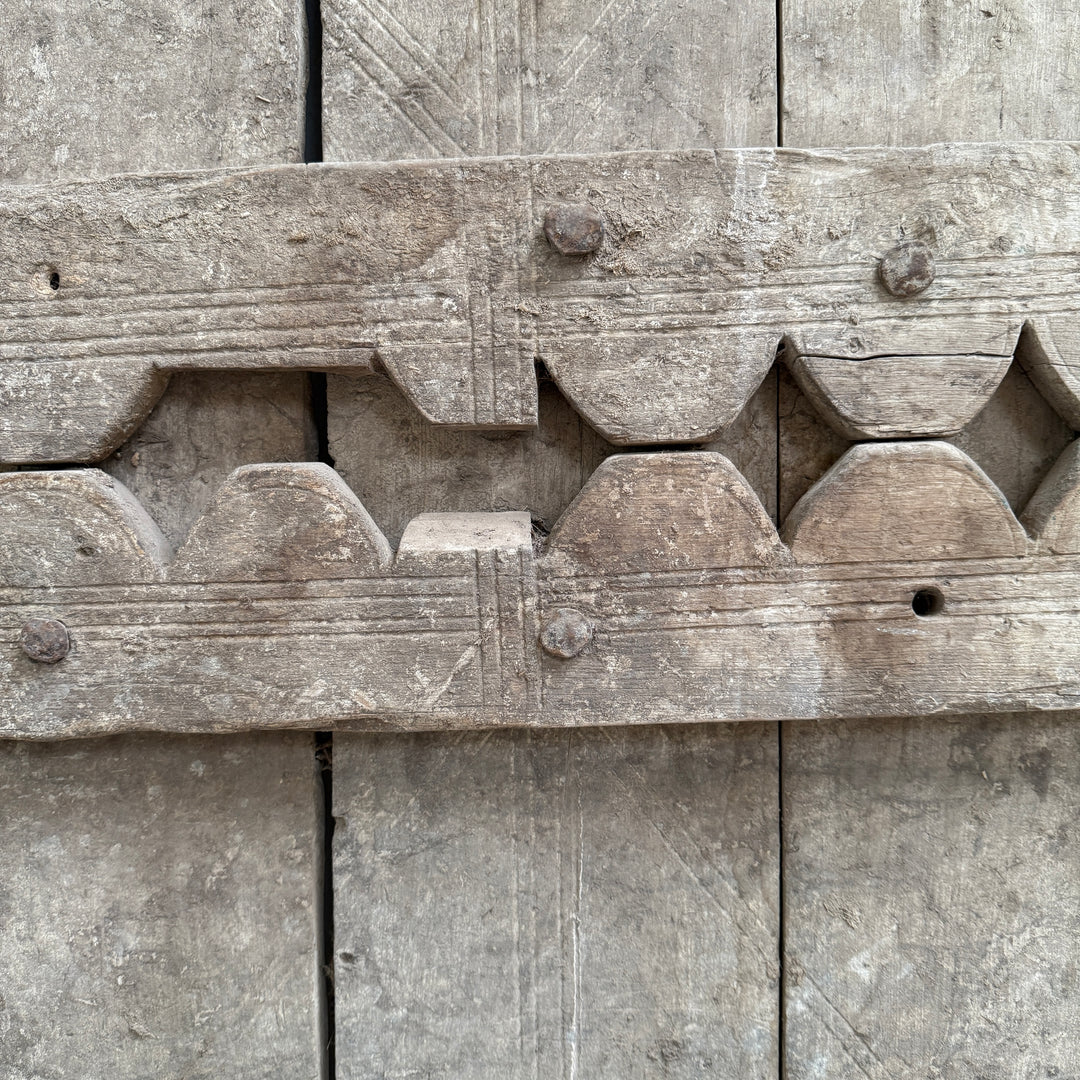 Close-up of a wooden architectural detail with intricate carvings on a textured surface.