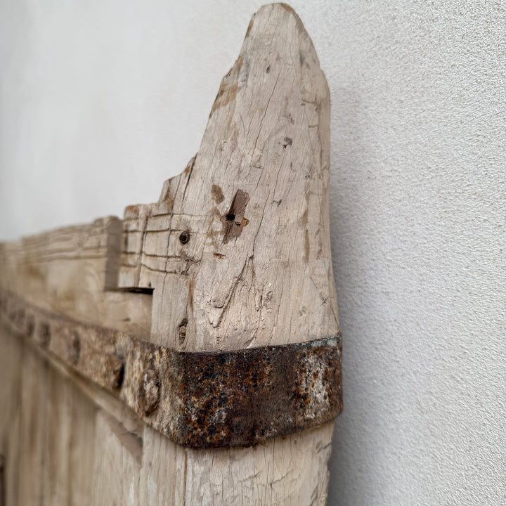 Close-up of a rustic wooden shelf against a light gray wall