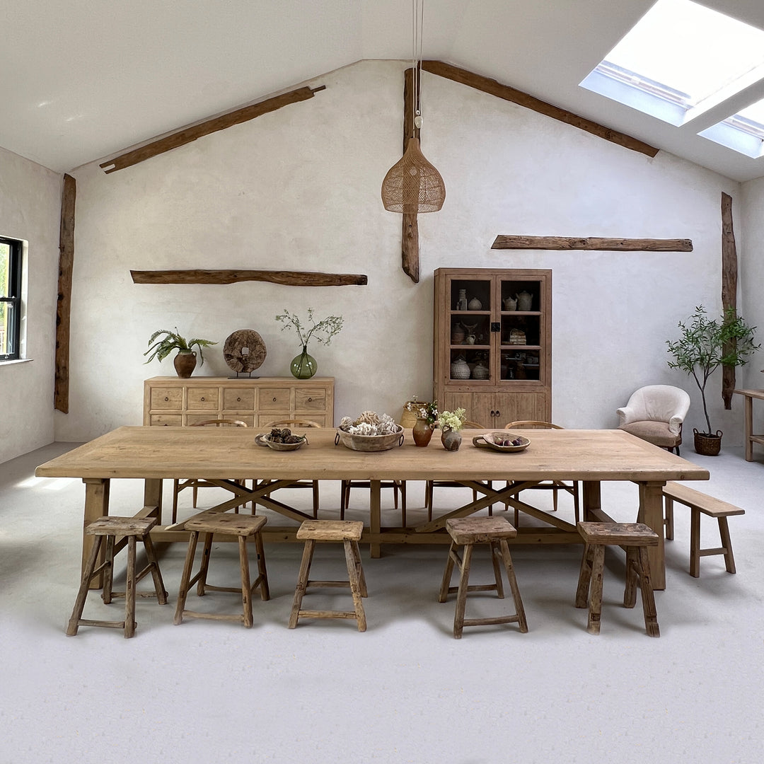 Large reclaimed pine dining table styled with wooden chairs in a luxury converted barn interior