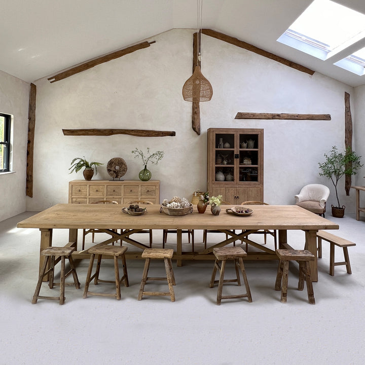 Large reclaimed pine dining table styled with wooden chairs in a luxury converted barn interior