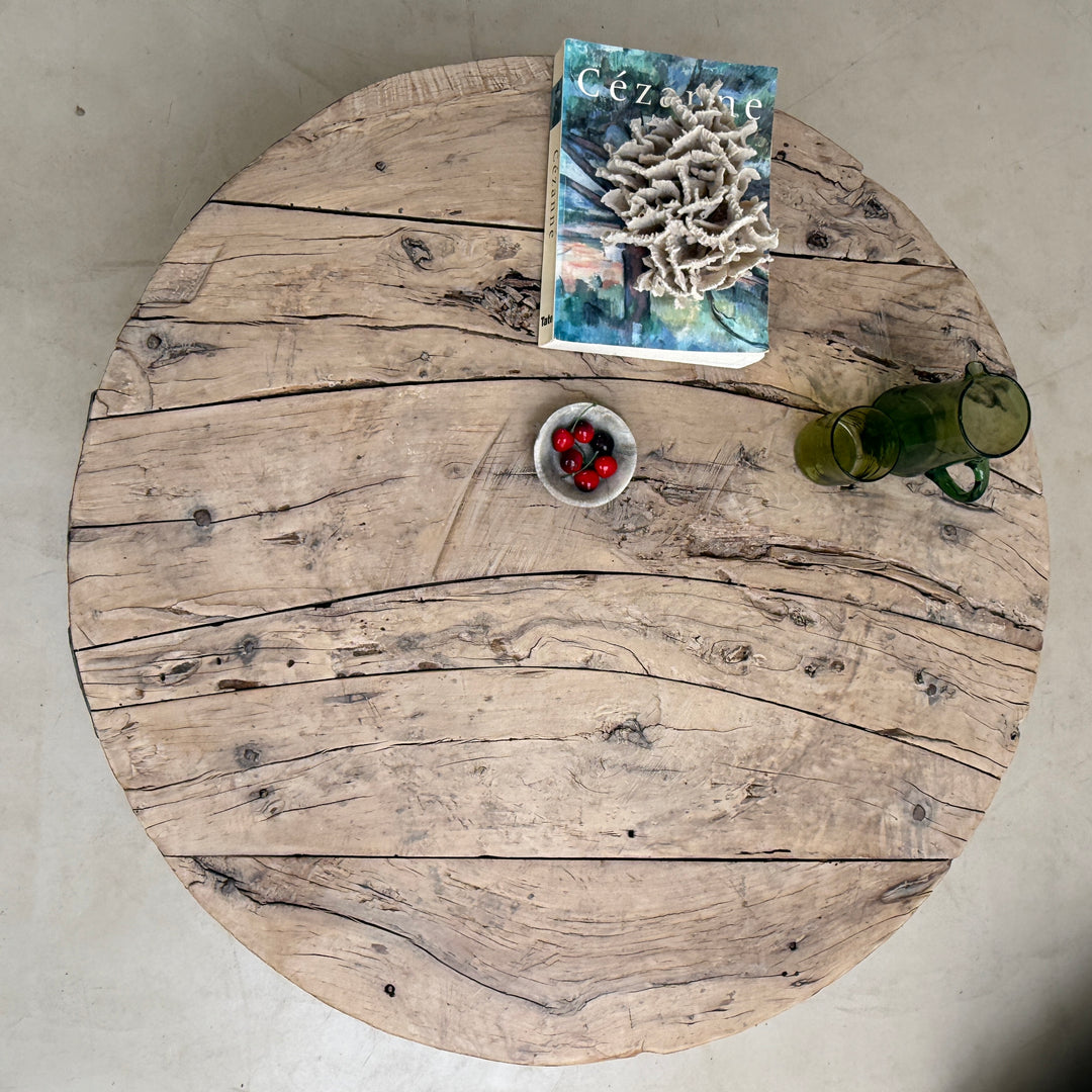 Round wooden table with a book, bowl of berries, and glasses on a light background