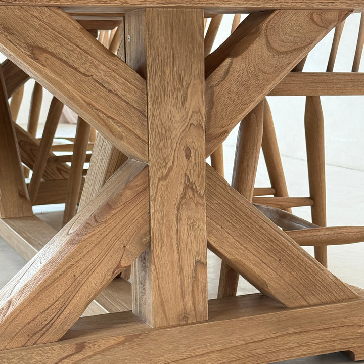 Side view of the large reclaimed oak dining table with a substantial cross-frame trestle base and classic wooden chairs.